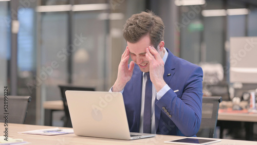 Businessman having Headache while Working on Laptop