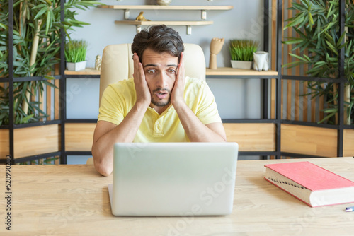 Close up portrait of shocked man with bugged eyes looking at laptop	