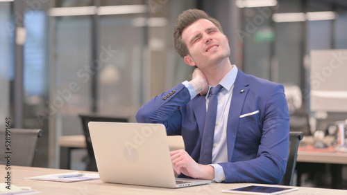 Businessman having Neck Pain while using Laptop in Office