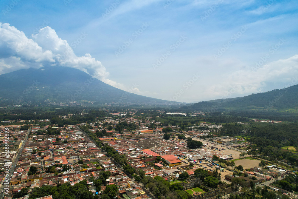 Antigua Guatemala With Volcan De Agua In The Background. Central American Colonial City Surrounded By Volcanos. Aerial Drone View.