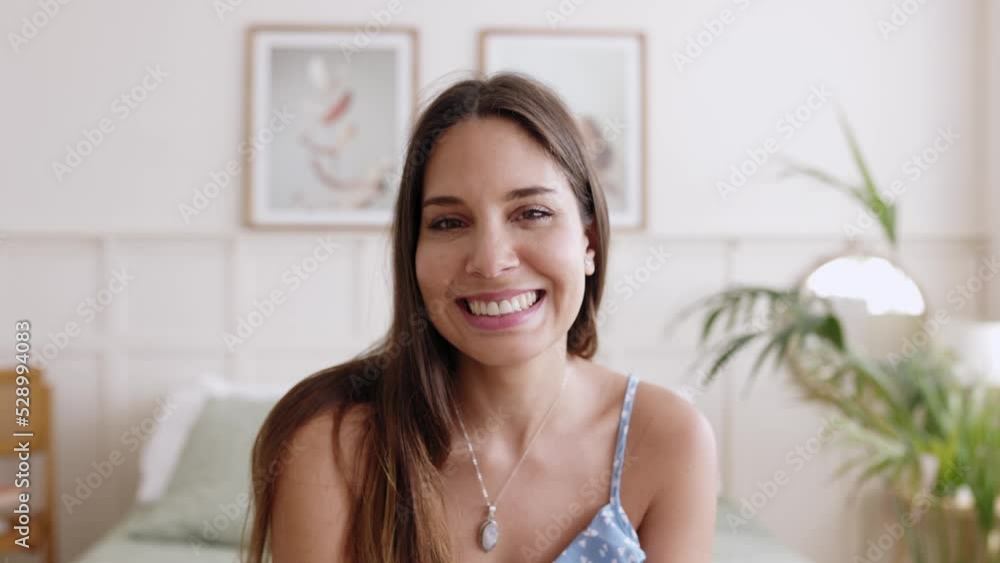 Face portrait of pretty young woman smiling at camera. Front view of cheerful millennial female sitting on bed in bedroom. Happy people concept. High quality 4k footage Face portrait of pretty young woman smiling at camera. Front view of cheerful millennial female sitting on bed in bedroom. Happy people concept. High quality 4k footage