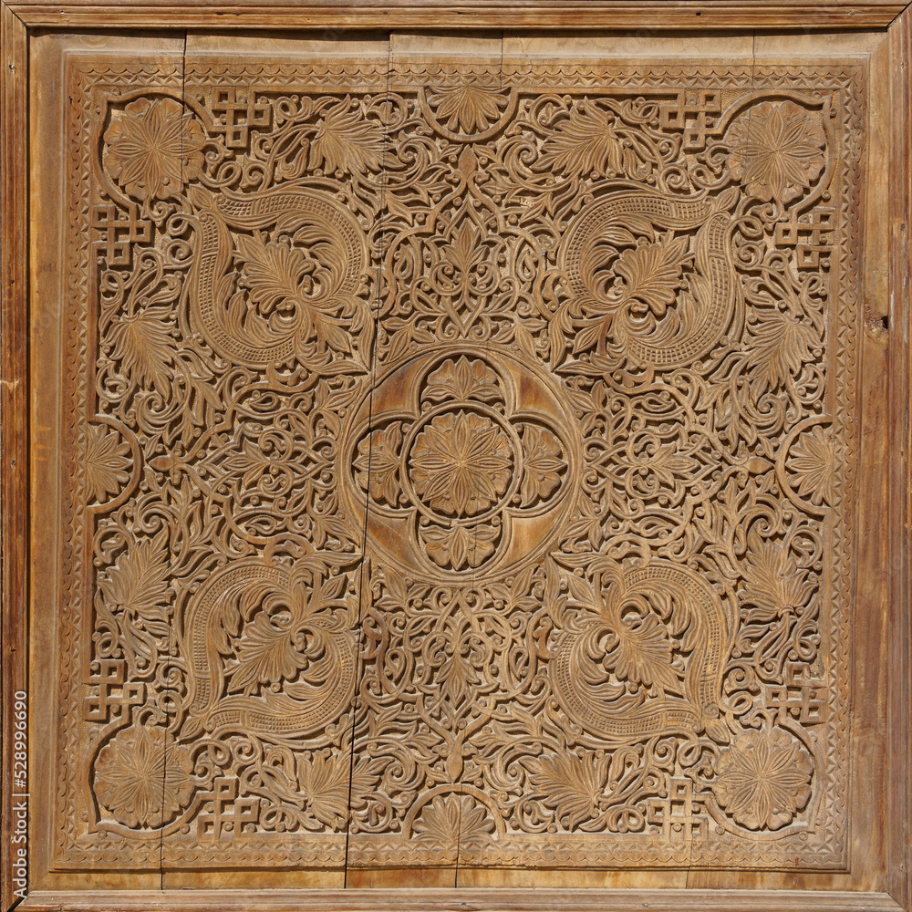 Closeup view of beautiful intricate wood carving of traditional islamic floral and geometric design on ancient door, Istaravshan, Sughd, Tajikistan