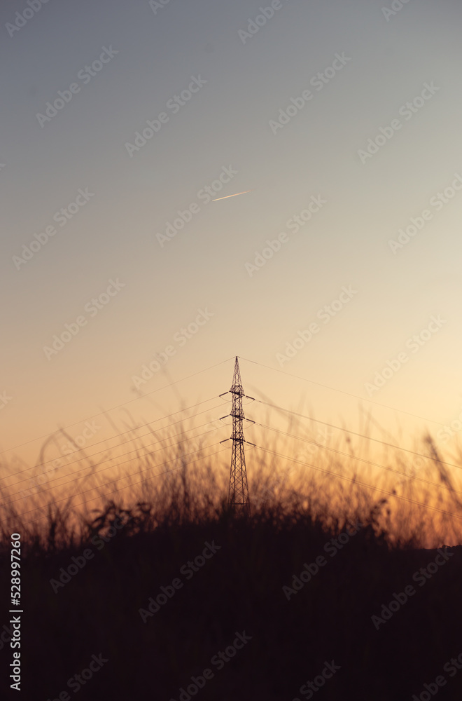 Silhouette of a power transmission tower with the sky after sunset in the background.