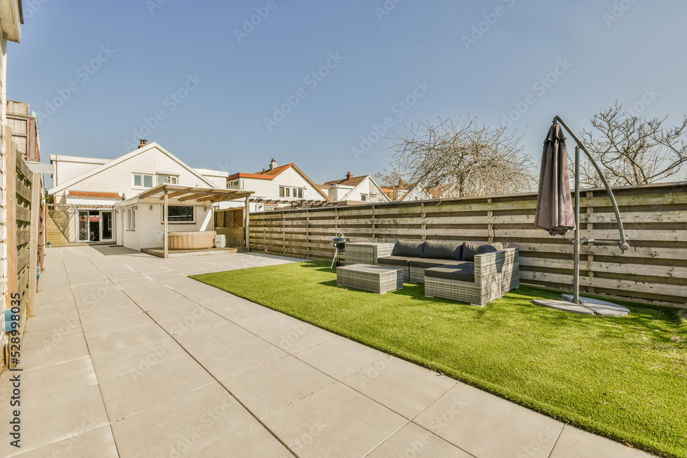 Backyard of a house with a sofa and a portable barbecue Backyard of a house with a sofa and a portable barbecue