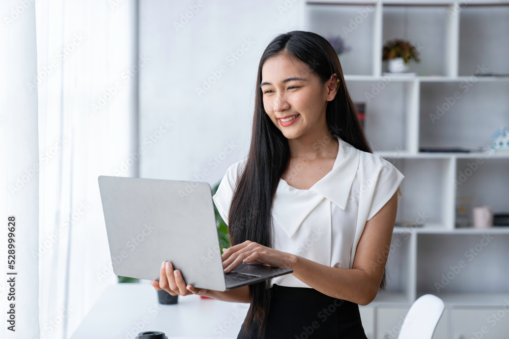 Beautiful Asian businesswoman holding a laptop computer and looking at the camera. Beautiful Asian businesswoman holding a laptop computer and looking at the camera.