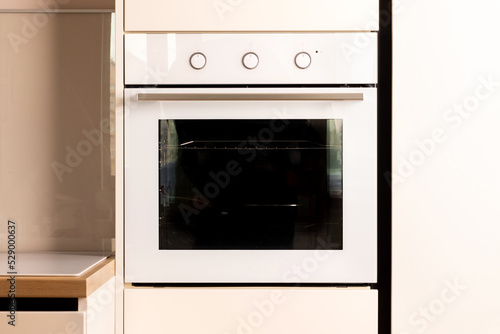 Modern bright white and beige kitchen with built-in oven closeup