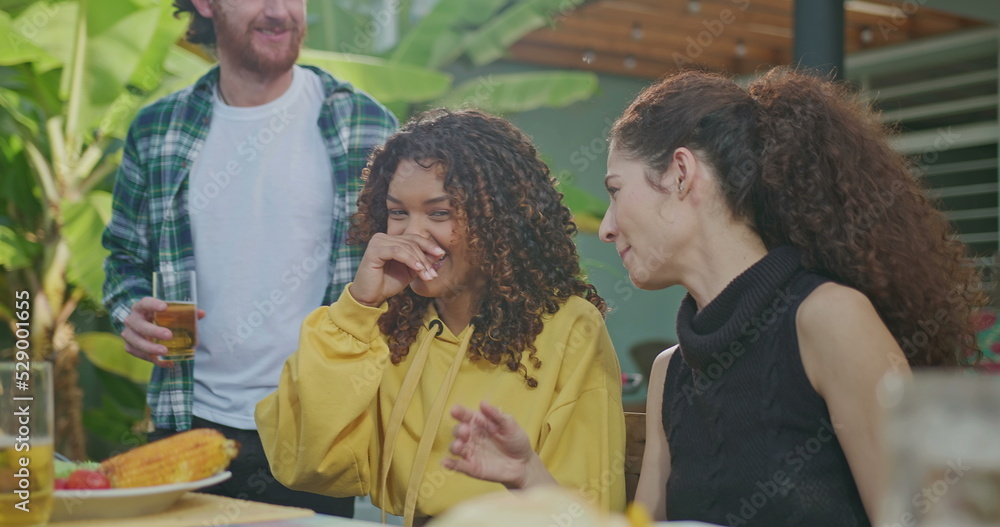 A group of friends are enjoying a barbecue on a sunny afternoon. Everyone is laughing and happy sitting at the table. A group of friends are enjoying a barbecue on a sunny afternoon. Everyone is laughing and happy sitting at the table.
