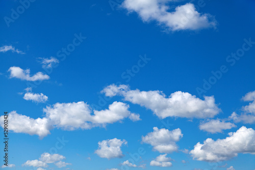 Fluffy white clouds in blue summer sky, perfect background.