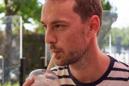 Man drinking a milkshake with a lost look