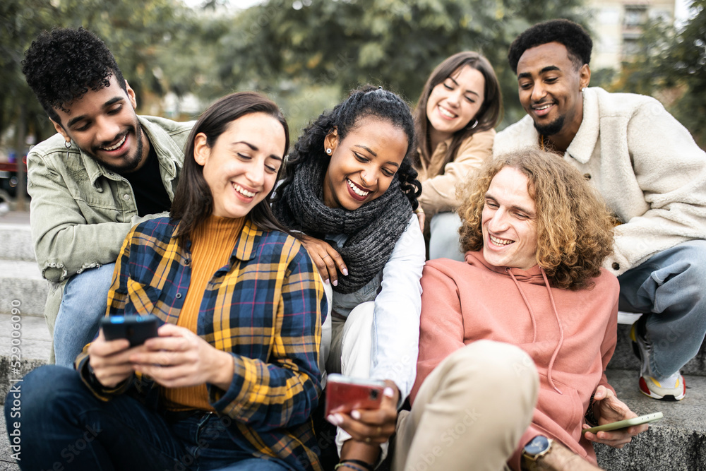 Young group of multiracial student friends using mobile phone in the city - Friendship, technology and new trends concept Young group of multiracial student friends using mobile phone in the city - Friendship, technology and new trends concept