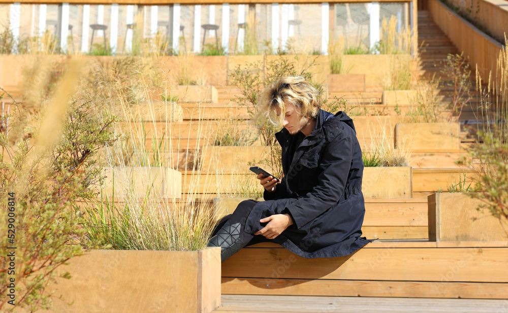 Lifestyle portrait of young man using a smartphone outdoors. Lifestyle portrait of young man using a smartphone outdoors.