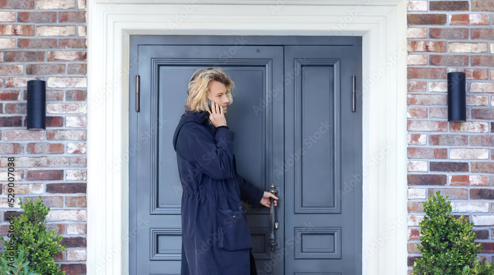 young man opening the door of his house.Inviting the guests young man opening the door of his house.Inviting the guests