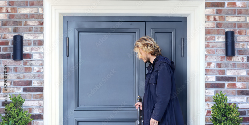young man opening the door of his house.Inviting the guests young man opening the door of his house.Inviting the guests