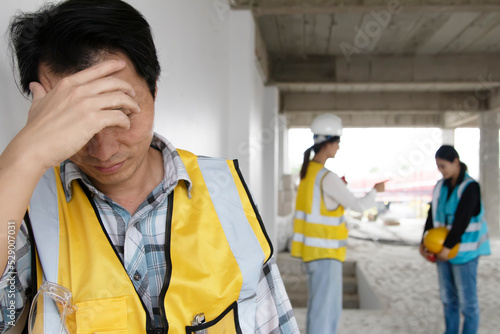 Fotografija Male worker stands stressed, anxious unhappy after being punished and criticized by an architect foreman with female colleague on a construction site being punished disciplinary