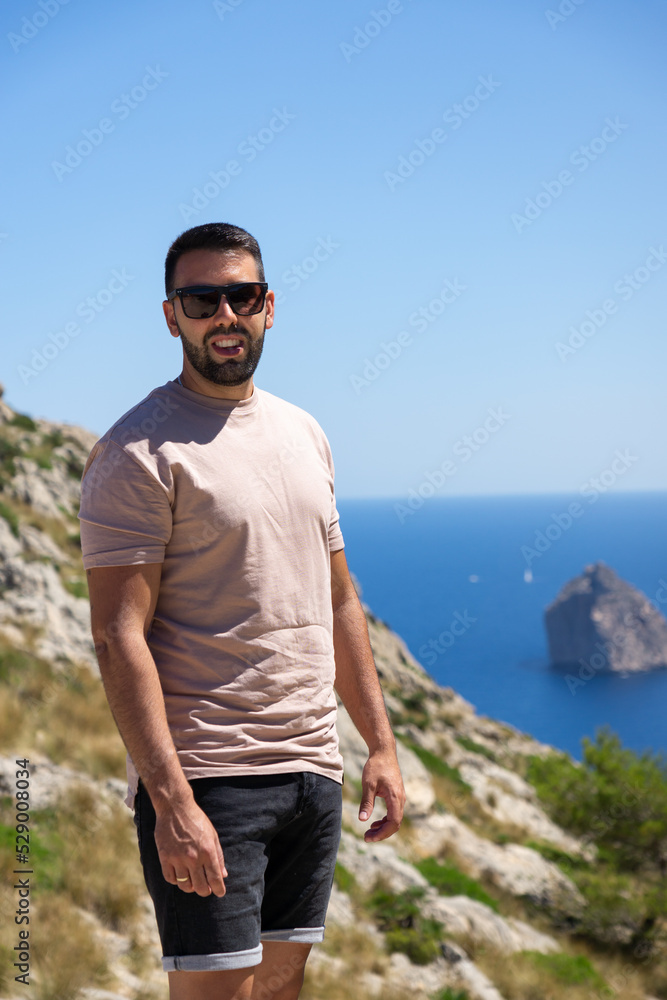 Young male tourist with sunglasses at the viewpoint es Colomer in Mallorca, Spain.