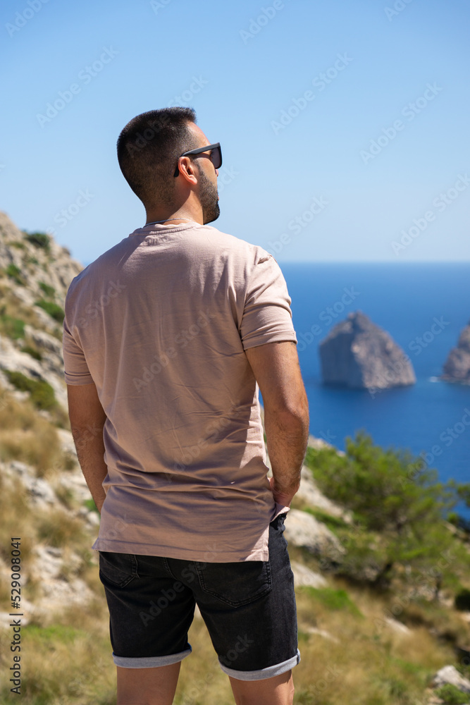 Young male tourist on his back looking at the Mediterranean Sea in Mallorca, Spain.