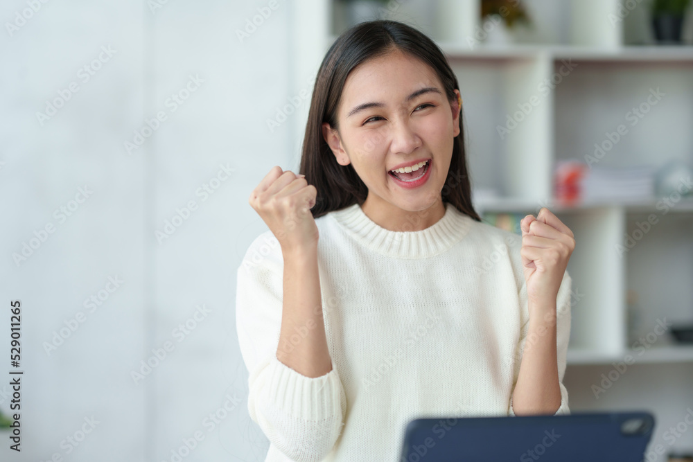 Pretty young Asian businesswoman sitting on a laptop Glad that the work came out, achieved the desired goal and was happy and satisfied with the results..