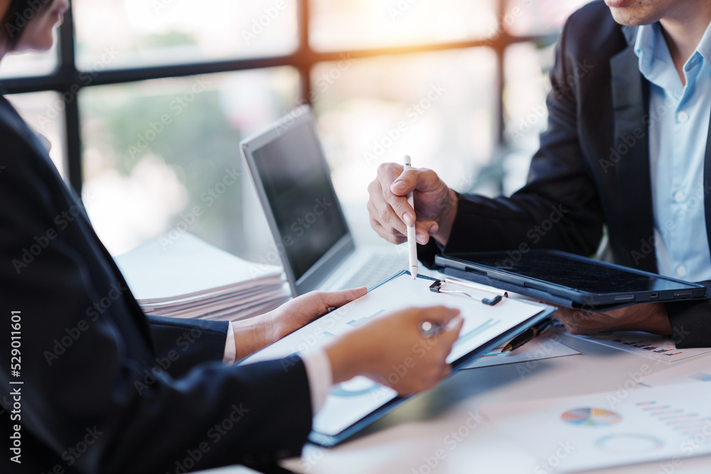 Business team together to make investment plan at the meeting. Close-up of business advisor pointing to graph and chart analyzing company financial report. Business team together to make investment plan at the meeting. Close-up of business advisor pointing to graph and chart analyzing company financial report.