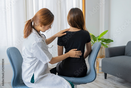 Female doctor doing physiotherapy to treat back. Female office worker back pain treatment. Doctor, chiropractor, office syndrome. photo