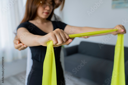 Physical therapist gives resistance band exercises. About the arms and shoulders of male office workers, office syndrome, male patient. Physiotherapy concept.