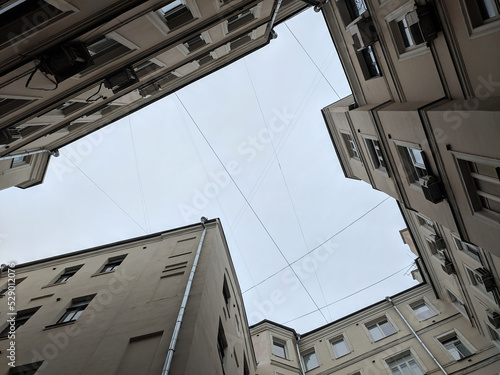 Enclosed courtyard (courtyard-well) with a low angle view. Sky surrounded by buildings and walls. Industrial frame. High quality photo