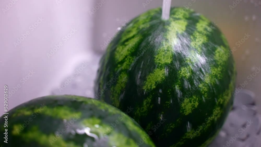 Striped ripe watermelons inside the kitchen sink under the water