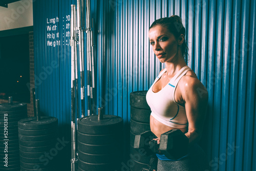 Fit blonde woman lifting weights training working out in Gym