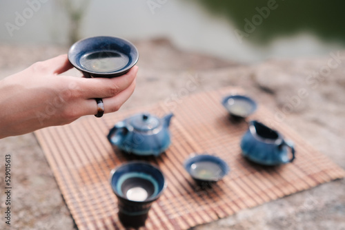 Girl hand holding blue cup with tea. A tea ceremony at rocks.