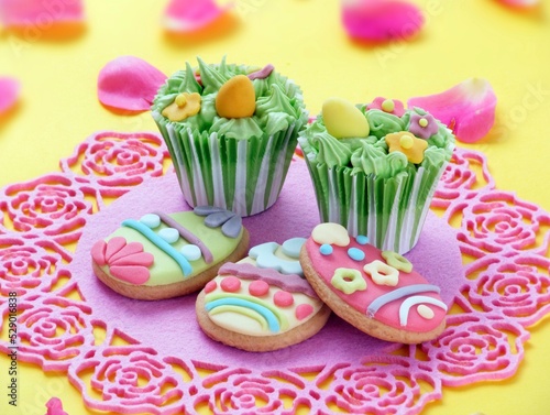 Easter egg cupcake design and cookies on yellow background.