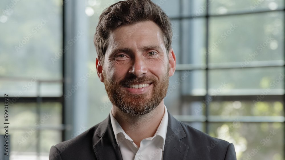 Adult calm strong confident Caucasian 40s bearded man looking at camera with serious expression smiling dental toothy company CEO leader manager worker businessman posing indoors in office with smile Adult calm strong confident Caucasian 40s bearded man looking at camera with serious expression smiling dental toothy company CEO leader manager worker businessman posing indoors in office with smile
