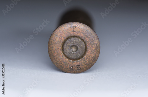7.62 mm caliber Mosin rifle cartridge made in Russia, Tula factory in 1915 year. Gray gradient background. T letter and 15 digit. Close up macro. WW1 First worls war. Hystory sample dug out cleaned. photo