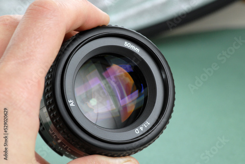 Fixed photo 50 mm lens in hand. Green background. Daylight shot. Window reflection.
