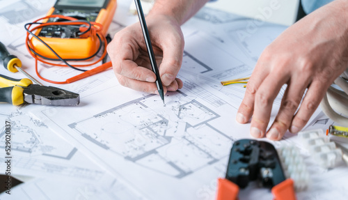 Man,repairer making electricity project in house.Repairs planning.Drawings,diagrams,plan for electrification of apartment,building.Devices,accessories,voltmeter,wires,screwdriver,pliers,tape measure