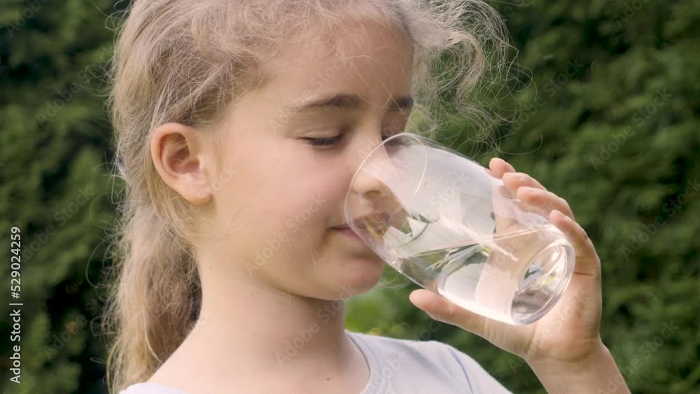 Thirsty Child Drinking Water From Glass Outdoors With Sun Shining. Cute Girl Drinking Glass Fresh Transparent Pure Filtered Water Slow Motion Kid Drinking Cup Water Healthy Body Care Healthy lifestyle Thirsty Child Drinking Water From Glass Outdoors With Sun Shining. Cute Girl Drinking Glass Fresh Transparent Pure Filtered Water Slow Motion Kid Drinking Cup Water Healthy Body Care Healthy lifestyle