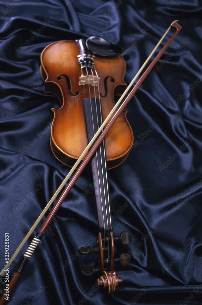 © SuperStock - Violin and a bow on blue fabric