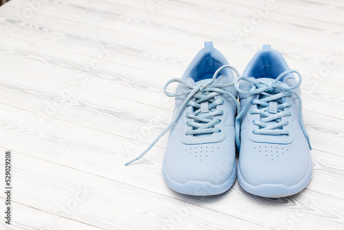 Blue sneakers stand on a white wooden background. Shoes with laces top view, flat lay. The concept of sport, running and outdoor activities. Take off your shoes at home.