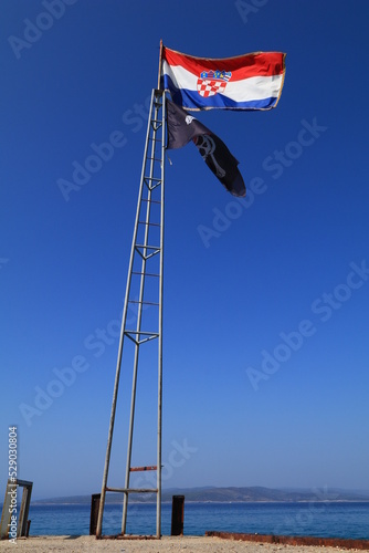 The national flag of Croatia displayed on the mast by the pirate tavern in the port