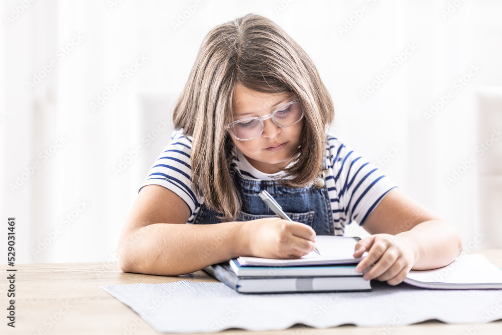 Bored girl writes homework into an exercise book Bored girl writes homework into an exercise book