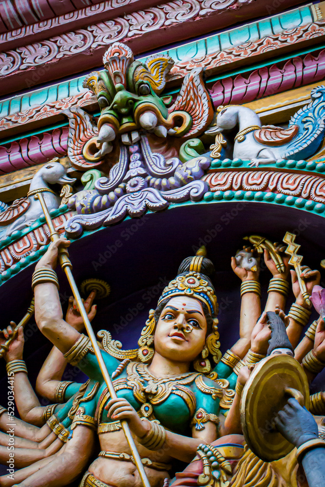 Fototapeta premium Closeup of Hindu Goddess Fighting off a Force of Evil on the Sikhara Tower of the Sree Dandu Mariamman Temple in Bengaluru, India