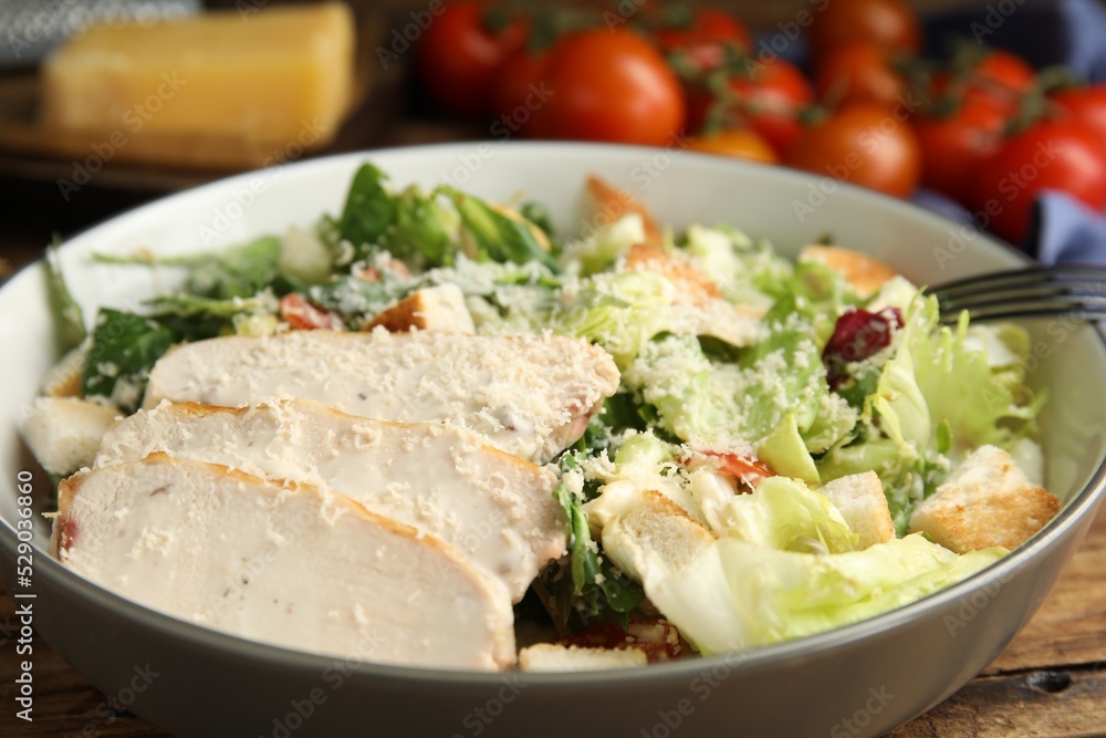 Delicious Caesar salad in bowl on wooden table, closeup Delicious Caesar salad in bowl on wooden table, closeup