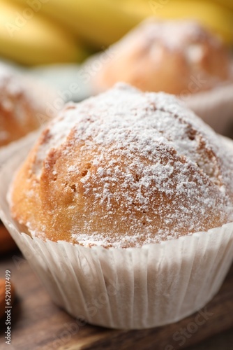 Tasty muffin powdered with sugar on table, closeup