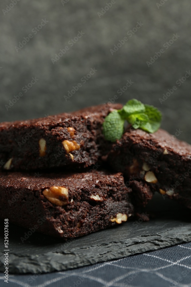 Fototapeta premium Delicious chocolate brownies with nuts and fresh mint on slate plate, closeup