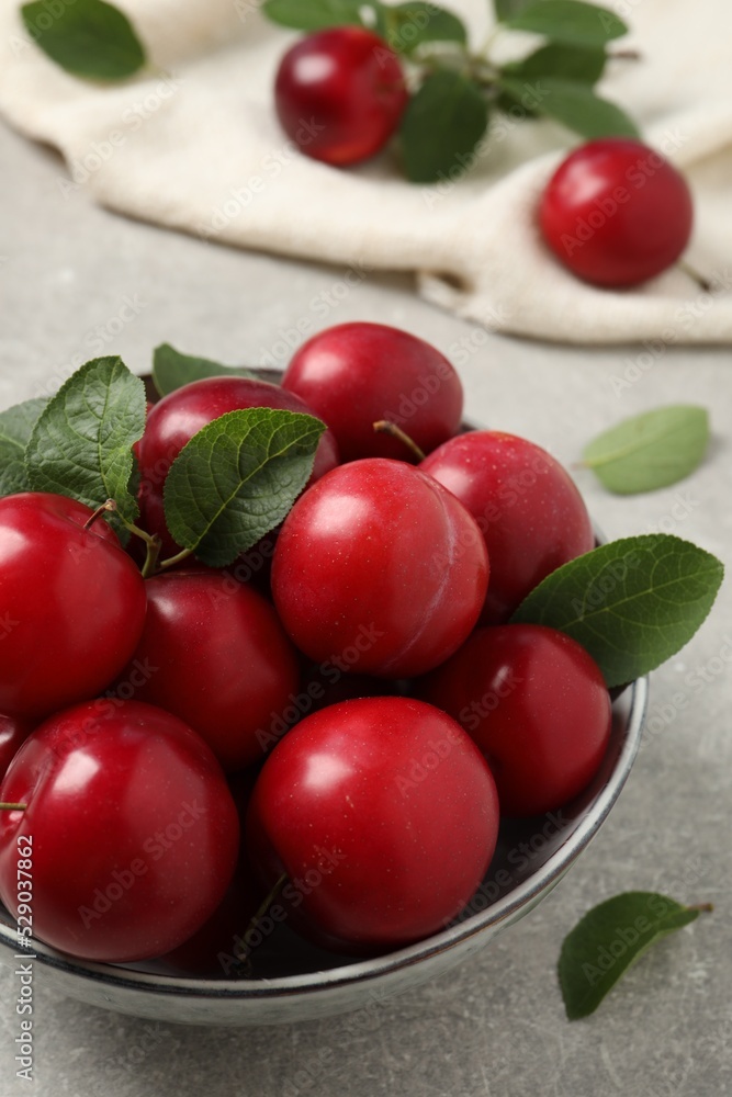 Delicious ripe cherry plums with leaves on light table Delicious ripe cherry plums with leaves on light table