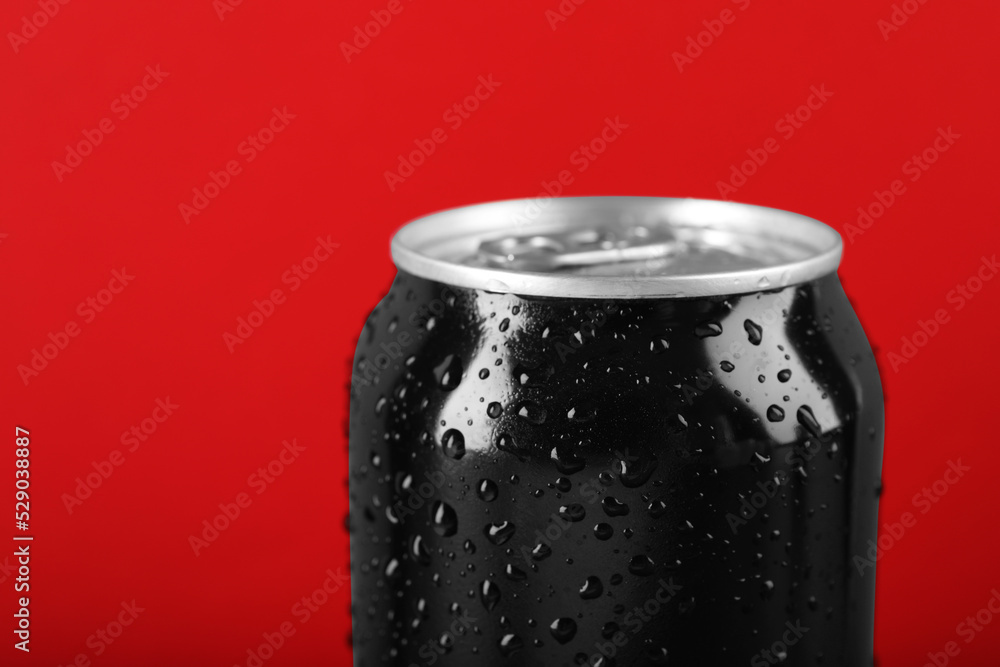 Black can of energy drink with water drops on red background, closeup Black can of energy drink with water drops on red background, closeup