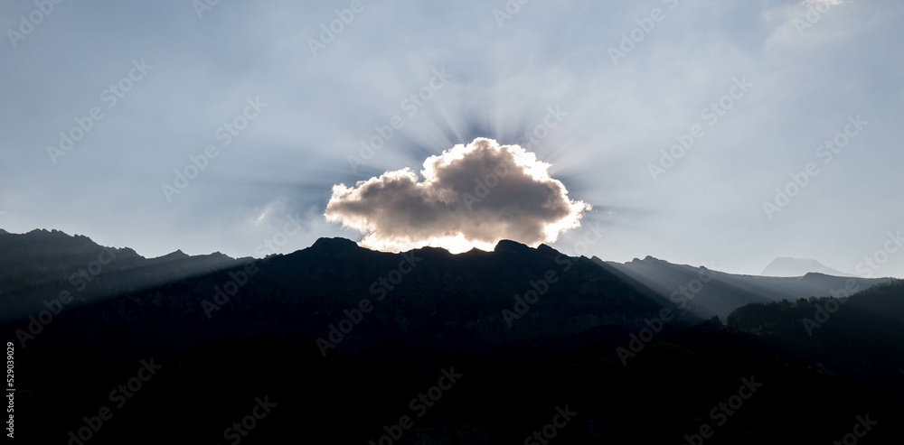 Sun rays break through the clouds in switzerland alps.