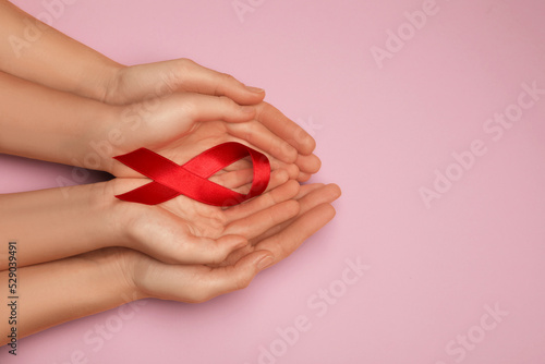 Woman and girl holding red ribbon on pink background, top view with space for text. AIDS disease awareness