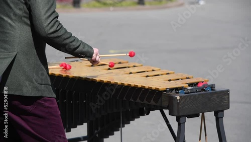Close-up view of male street performer playing on wooden xylophone on city square in a sunny day. 4K resolution real time video. Musical instruments theme.