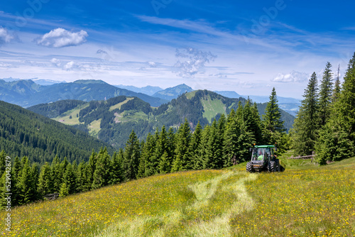 Tractor in a field in front of alpine mountain range
