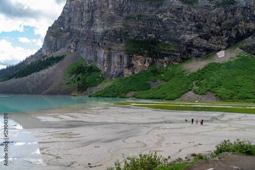 The marshy glacial silt area of Lake Louise, in Banff National Park. A family with a dog in the distance, walking on the sand photo