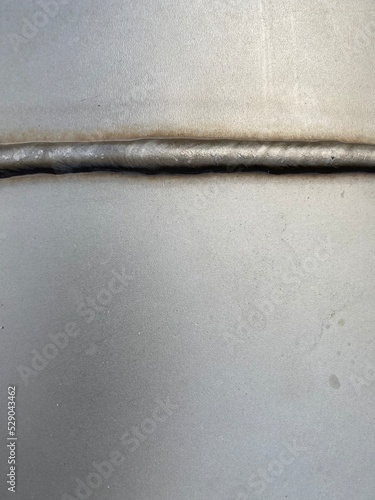 A weld seam on a gray stainless steel tank
